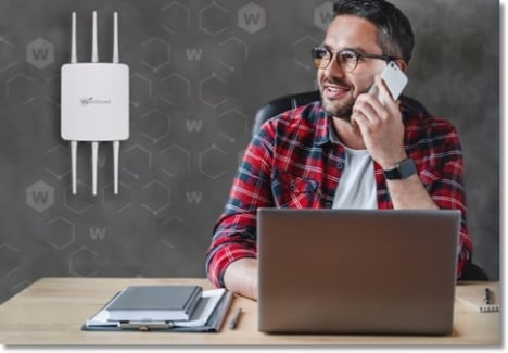 WatchGuard AP access point on the wall behind a man at his laptop talking on a mobile phone