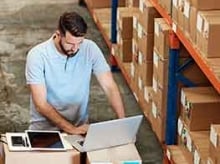 Man working on a laptop in a warehouse 
