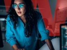 Woman in blue shirt and glasses in a dark office