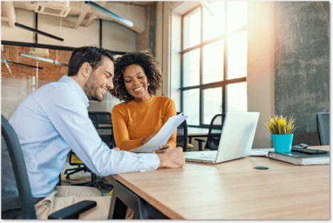 Woman in an orange top showing a paper to a man in a blue dress shirt 