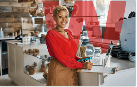 Woman in a red blouse standing in a cafe with her laptop open